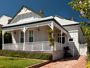 Exterior Front Exterior with White Fencing and Painted Brick around Porch and Grey Gable Detailing